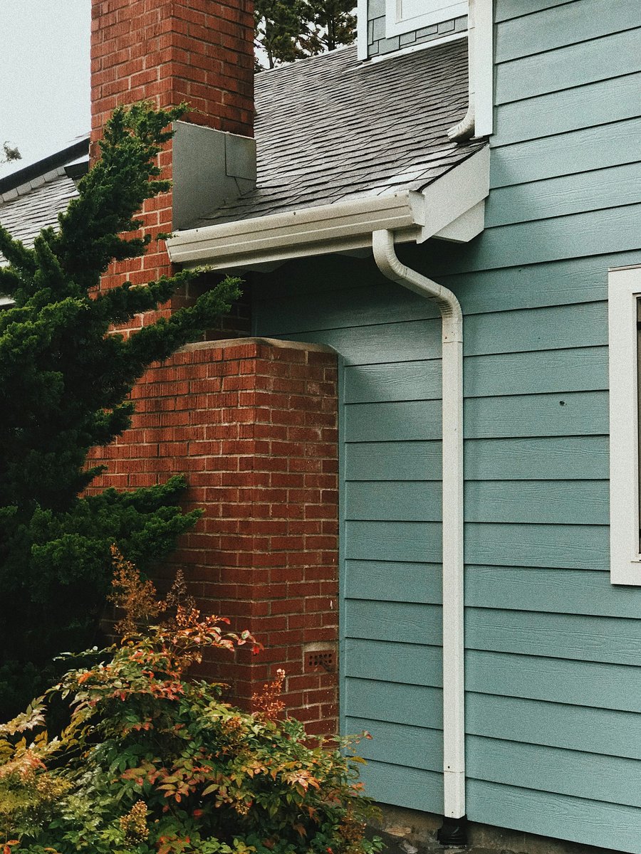 A gutter and downspout at a building roof edge